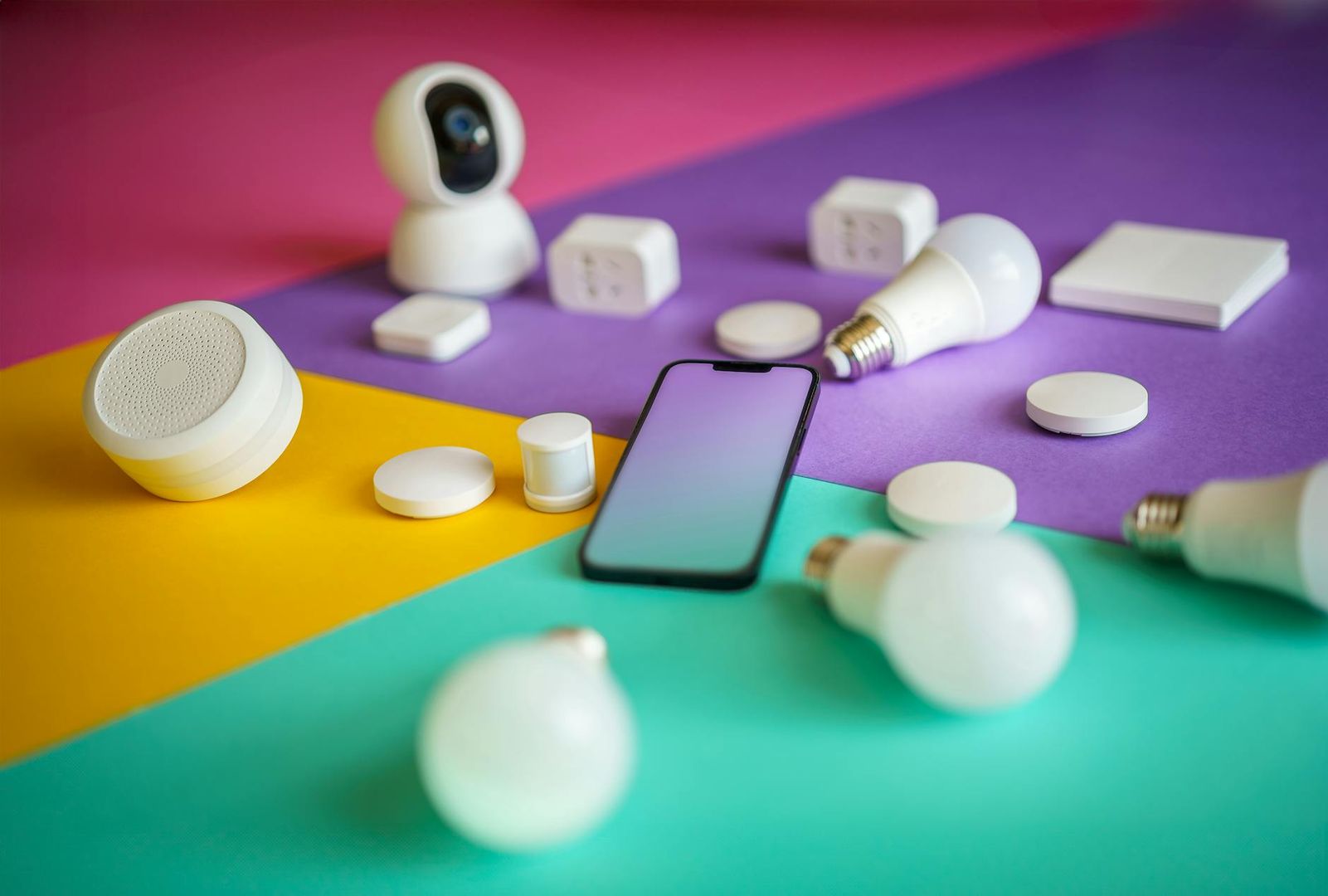 En samling vita smarta hemenheter och en smartphone på en färgglad bakgrund.